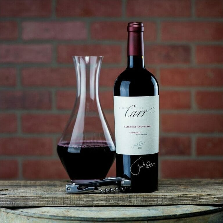 bottle of signed coombsville cabernet sauvignon on wooden slab with decanter and bottle opener