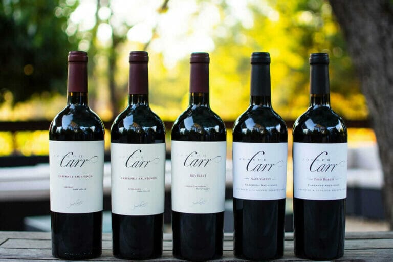 five bottles of carr red wine varieties lined up on table outside